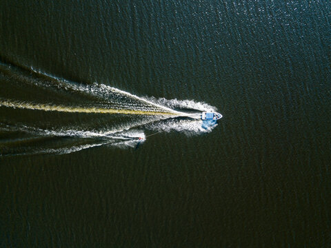 Aerial drone view. Wake surfing behind a boat on the river on a sunny summer day.