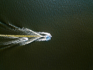 Naklejka premium Aerial drone view. Wake surfing behind a boat on the river on a sunny summer day.