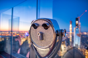 Binoculars with city view at sunset