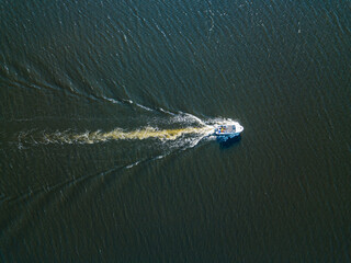 Naklejka premium Aerial drone view. The motor boat is sailing along the river. Sunny summer day, small waves.