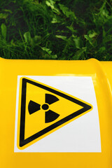 The nuclear sign on a yellow metal barrel on the green grass, close up. Radiation hazard symbol...