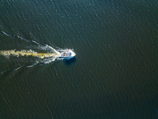 Aerial drone view. The motor boat is sailing along the river. Sunny summer day, small waves.