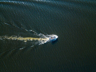 Aerial drone view. The motor boat is sailing along the river. Sunny summer day, small waves.