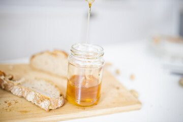 Honey jar and a slice of bread on a wooden board