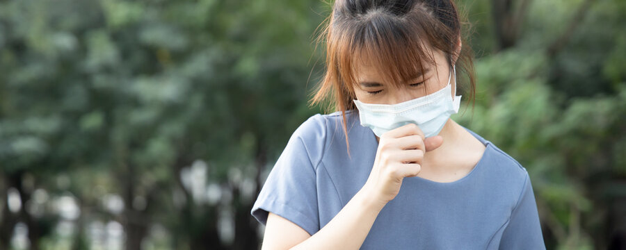Banner of sick coughing asian woman wearing face mask in outdoor park, concept of coronavirus symptomatic infection, social distancing, new normal lifestyle of pre coronavirus cure, COVID-19 vaccine