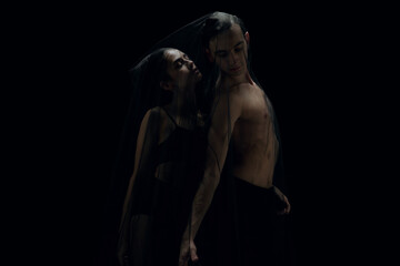 Fototapeta na wymiar Touch. Graceful classic ballet dancers isolated on black studio background. Couple in minimalistic dark cloth look graceful, inspired. The grace, artist, movement, action and motion concept.