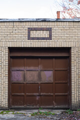 Weathered brown single car residential garage door inset in a light brick wall, creative copy space, horizontal aspect