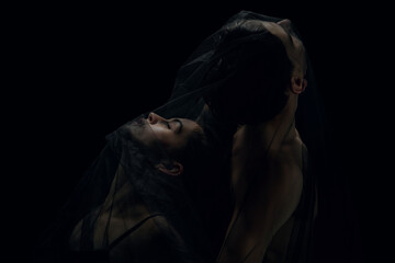 Dark. Graceful classic ballet dancers isolated on black studio background. Couple in minimalistic...