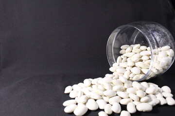 beans poured out of a glass jar on a black background of a copy of the space