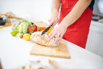 Male hands slicing bread on a cutting board