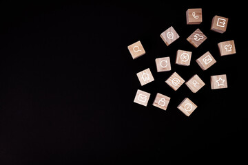 Set of white computer icons on wooden cubes scattered on black background