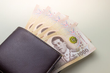 leather wallet and Thai banknotes, five thousands baht on beige background