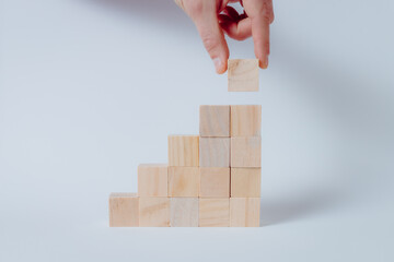 Hand completing business growth conceptual on wooden cubes. White background