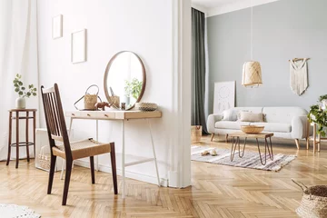 Fotobehang Boho Modern concept in design home interior of open space with wooden desk, coffee table, sofa, chair, plants, mirror, macrame and elegant accessories. Stylish and minimalistic home decor. Template.  © FollowTheFlow
