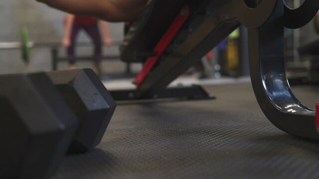 muscular man on workout weight bench dropping heavy dumbbell on gym floor after finished training set. exhausted man release dumbbell due to tired. copy space for advertising. 