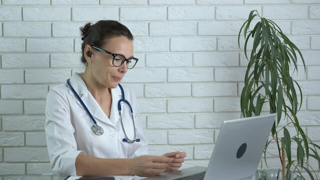 Making medical conference call. A nice smart woman doctor in a white coat speak with patients online on video link.