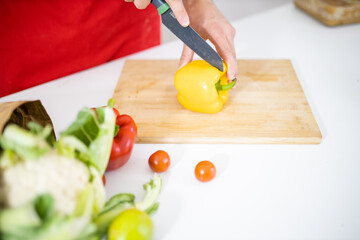 Male hands slicing a bell pepper on a cutting board
