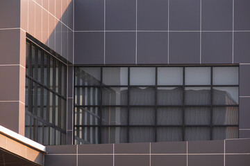 Sunlight and shadow on geometric pattern of glass wall and brown aluminum composite tile on modern building in perspective view  