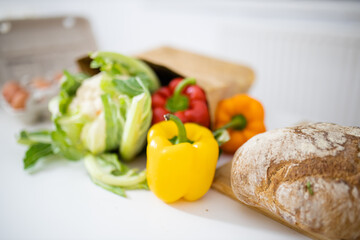 Bell peppers and a cauliflower on white table next to bread