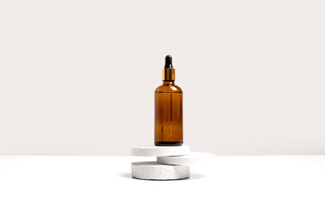 Serum, oil, acid, lotion in brown dropper glass bottle on gray concrete pedestals side view with copy space. Spa products. Organic, bio, natural cosmetic. Beauty, skincare concept. Stock photo