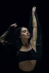 Fototapeta na wymiar Drawning. Graceful classic female ballet dancer isolated on black studio background. Woman in minimalistic black cloth looks graceful, inspired. The grace, artist, movement, action and motion concept.
