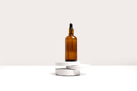Serum, oil, acid, lotion in brown dropper glass bottle on gray concrete pedestals side view with copy space. Spa products. Organic, bio, natural cosmetic. Beauty, skincare concept. Stock photo