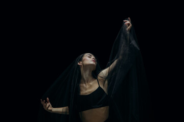 Night. Graceful classic female ballet dancer isolated on black studio background. Woman in...