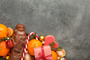 Flat lay composition with chocolate Santa Claus candies on grey table. Space for text