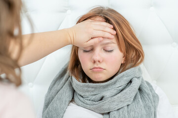 Mother touches the forehead of a sad girl, checking the temperature