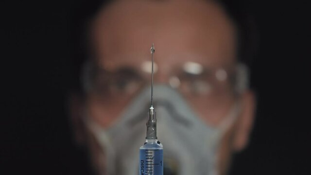 Doctor holds the syringe in his hand and presses the valve to release the air from the syringe,drops flow down the needle, preparing to injection.