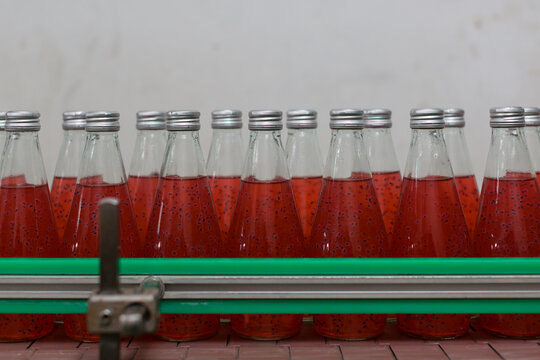 Product Of Basil Seed With Fruit On The Conveyor Belt In The Beverage Factory. Bottling Line For Processing And Bottling Basil Seed With Fruit Into Bottles. Food, Health And Beverage Industry