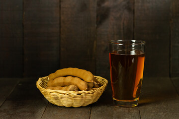 tamarind juice and tamarind fruit in wicker basket on wooden background copy space