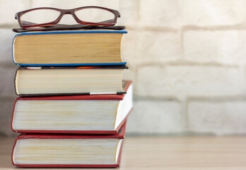 A stack of old thick books and glasses on the table.