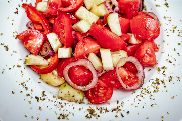 Close-up fresh tomato, paprika, cucumber and onion salad on the table