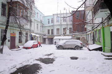 City after blizzard. Cars covered with snow parked on a yard. Kyiv, Podil district, Ukraine