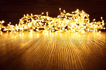 Beautiful glowing Christmas lights on wooden table. Space for text