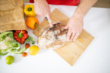 Male hands slicing bread on a cutting board