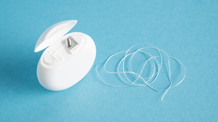 Dental flossing case and white thread on a blue background. Dental care. Interdental floss and box. Flossing tool