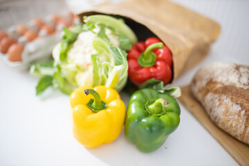 Bell peppers and cauliflower on white table next to bread