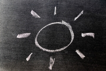 Fototapeta na wymiar White color chalk hand drawing in sun with ray shape on blackboard background