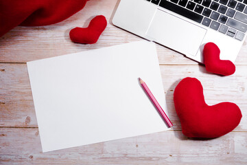 Office flat lay with red toy hearts and black keyboard of silver laptop. Write wish on white piece of paper for Valentines day on February 14. Celebrate Valentines day.