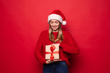Christmas woman holding christmas gifts smiling. Cute beautiful Caucasian santa woman isolated on red background