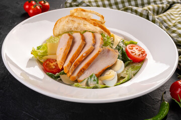 salad with chicken and chips in a white plate on a dark background. Caesar Salad