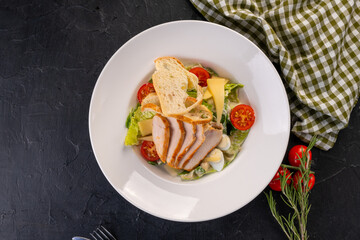 salad with chicken and chips in a white plate on a dark background. Caesar Salad