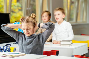 Fototapeta Stressed school girl child, pupil, bullying victim being by classmates in classroom during lesson with a blur background in classroom. obraz