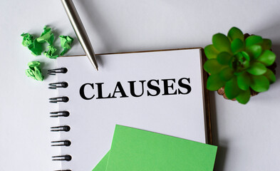 CLAUSES - word in a notebook with a pen, a green paper and a cactus on a white background