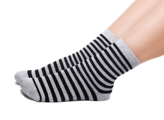 Female legs in warm striped black and grey socks isolated on white background.