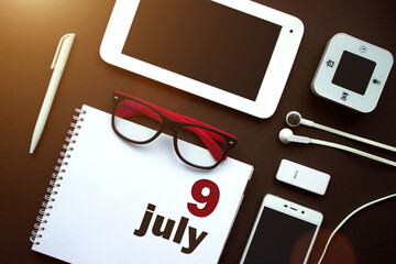 July 9th. Day 9 of month, Calendar date. Office workplace with laptop, notebook, office supplies...