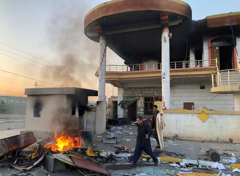 Men are seen outside the headquarters of the Kurdistan Democratic Party (PDK) after it was burnt during anti-government protests on the outskirt of Sulaimaniyah