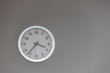 Big clock hanging on grey wall. Classic round wall clock on the grey background. Round clock on office wall